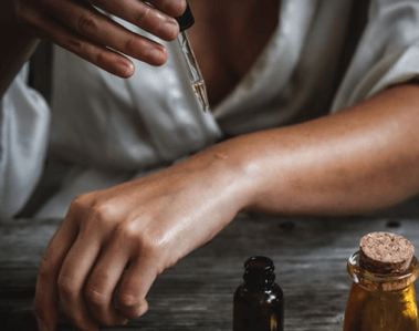 A person enjoying self care and nourishing their skin with oils.