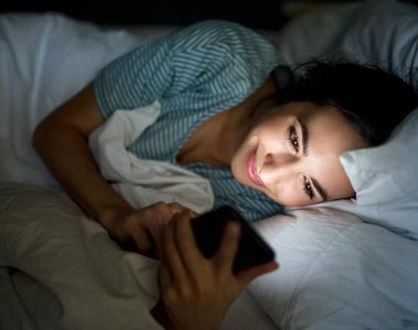 Woman browsing on her phone late night in bed.