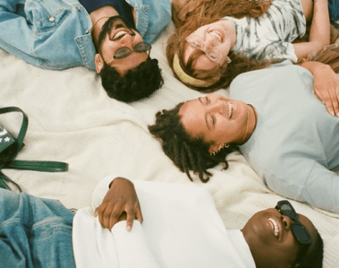 A group of diverse friends happily lying down together.