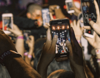 A crowd of people holding smartphones and recording at a live concert.