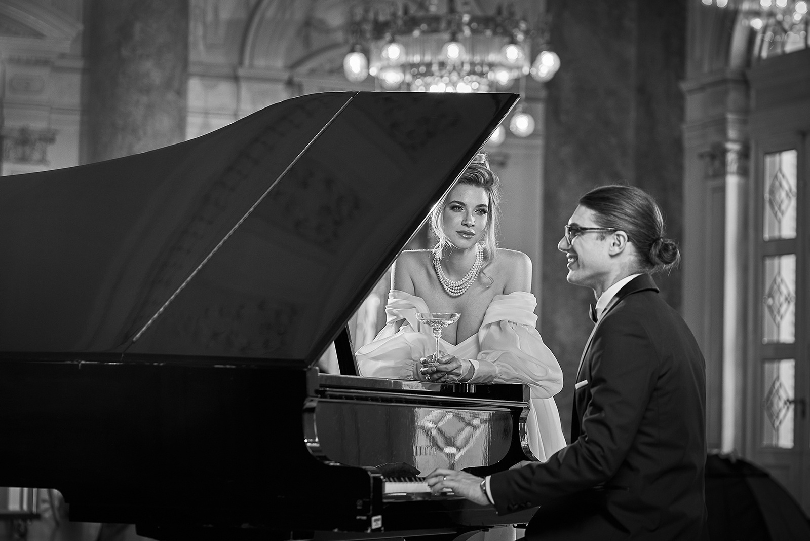 Bride and groom enjoying themselves in romantic atmosphere by piano, black and white photography