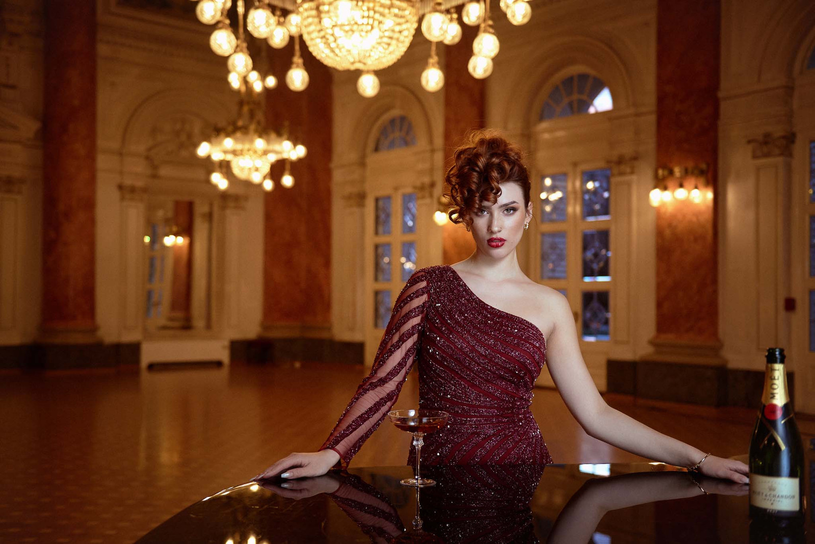 Beautiful bride in red dress posing in romantic atmosphere with champagne