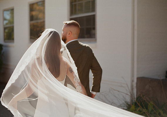 Bride and groom walking through Hudson Valley field at sunset, 35mm film photography.