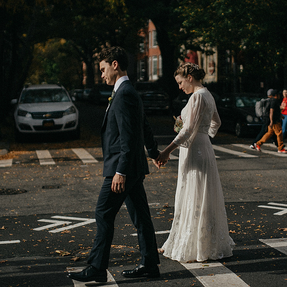 Beautiful wedding couple walking down the street in Brooklyn, New York. The light is dramatic and embraces the couple. Villetto Photography.