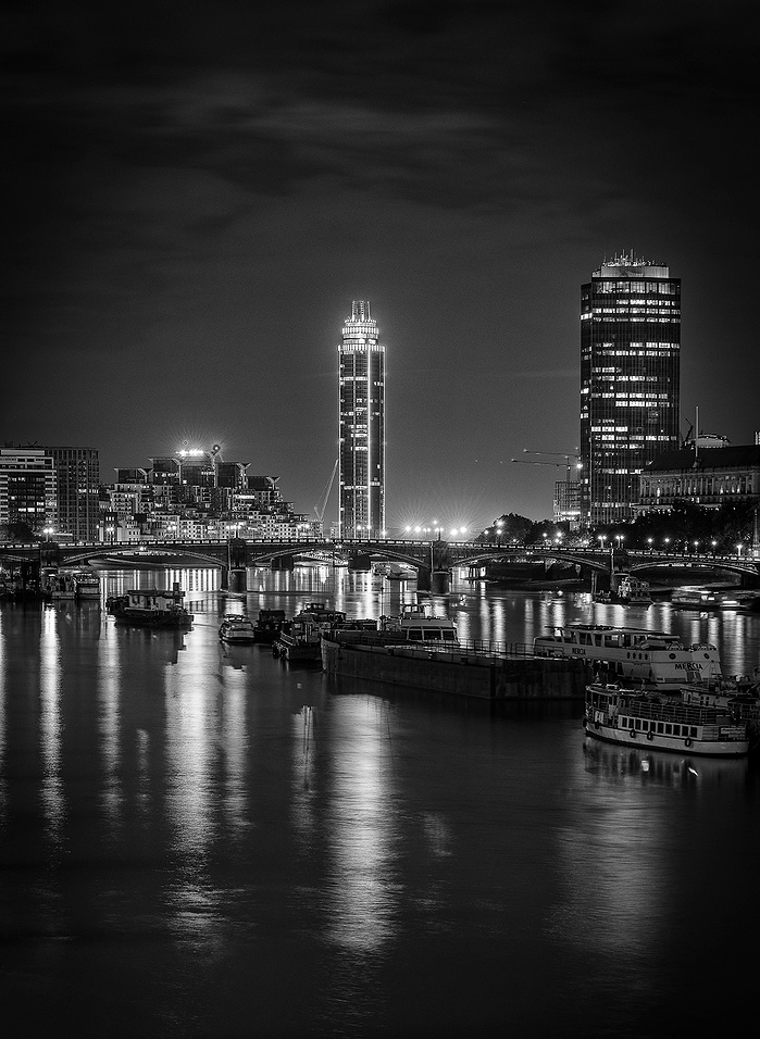 A long exposure black and white photo of The Thames and bridge at night by Mark Burley