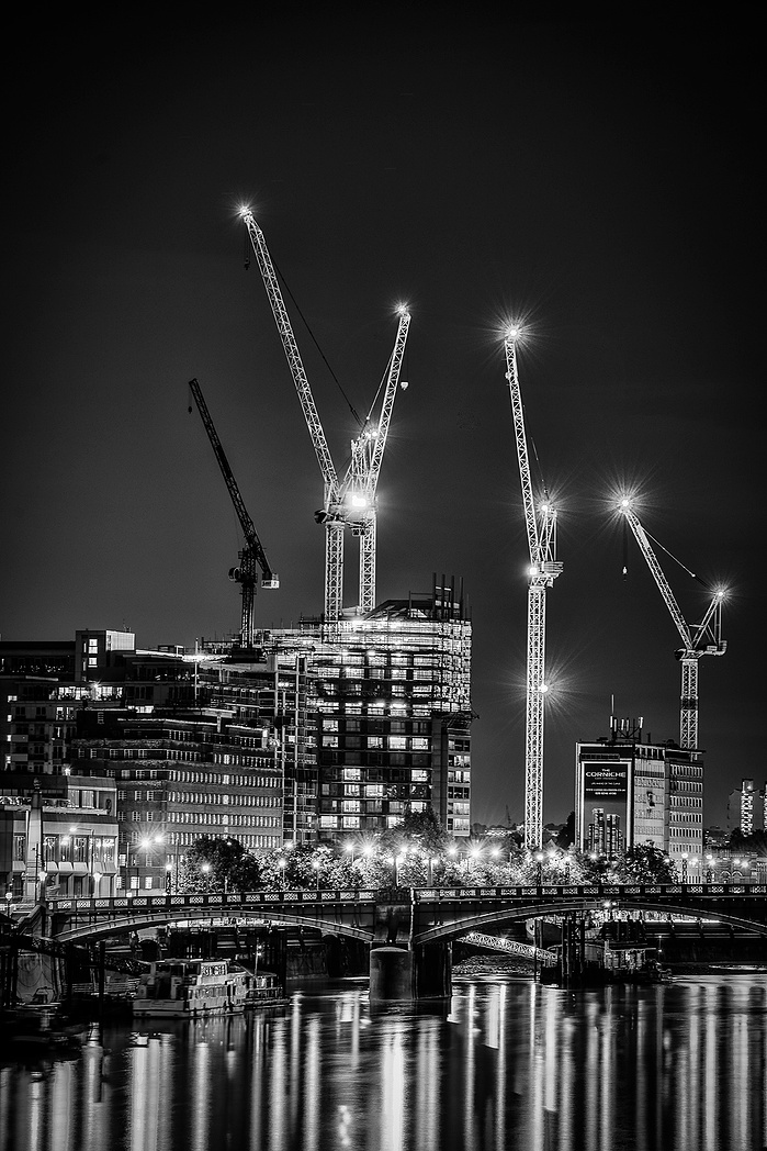 A black and white photo of City cranes at night by Mark Burley