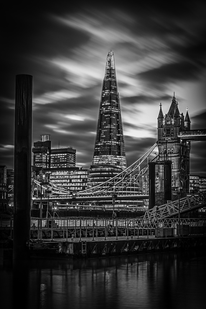 A black and white photo of the Shard by Tower Bridge and the Thames at night by Mark Burley