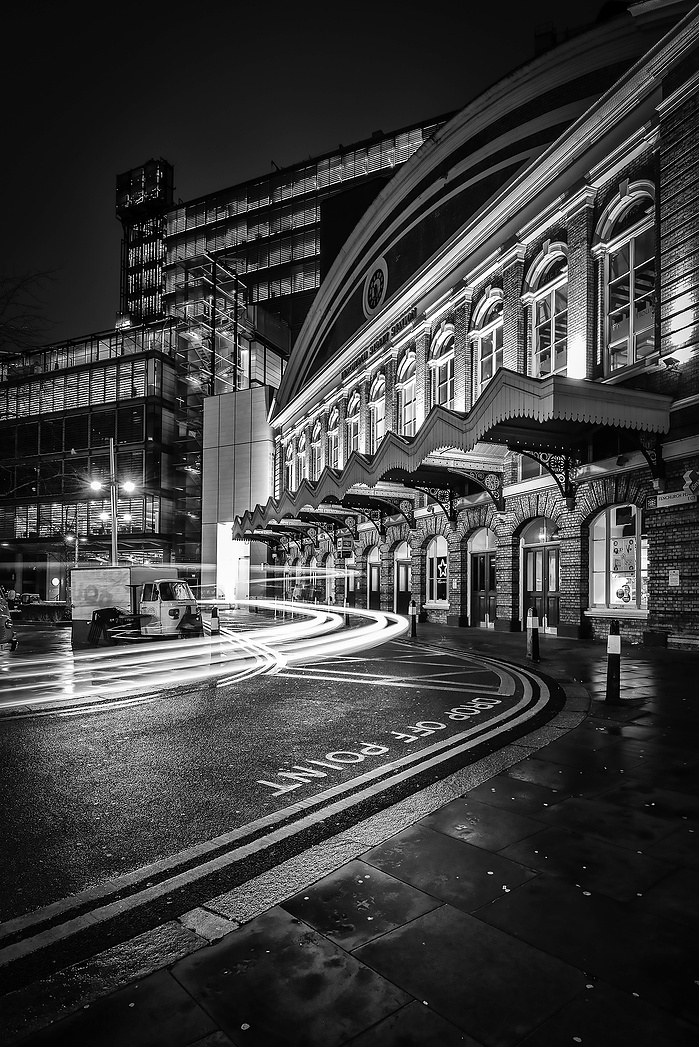 A black and white photo of Fenchurch Street Station and light trails at night by Mark Burley
