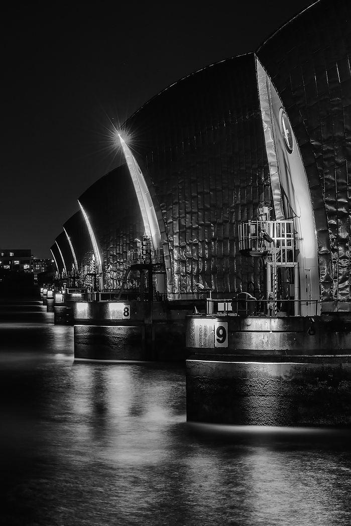 A long exposure black and white photo of The Thames Barrier at night by Mark Burley