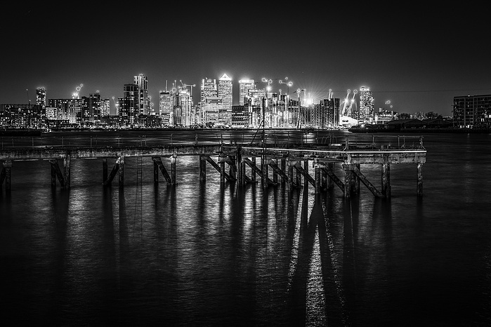 A long exposure black and white photo of Canary Wharf from the Thames Barrier (at night) by Mark Burley