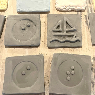 A photo of four tiles: one that is stamped with the braille letter 