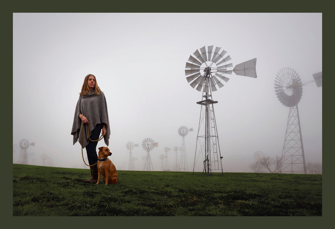 Portrait of woman with her dog on a windmill farm.