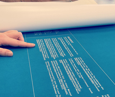 A close-up of the last page of the essay with someone's hand pointing to the text. Other pages of the essay are rolled up alongside.