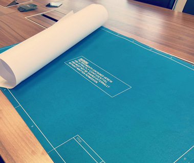 The first page of the essay rolled out on a large conference table.