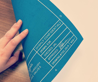 A close-up of the bottom-right hand corner of one of the essay pages. It shows the detail of the page border, in the style of an engineering blueprint.