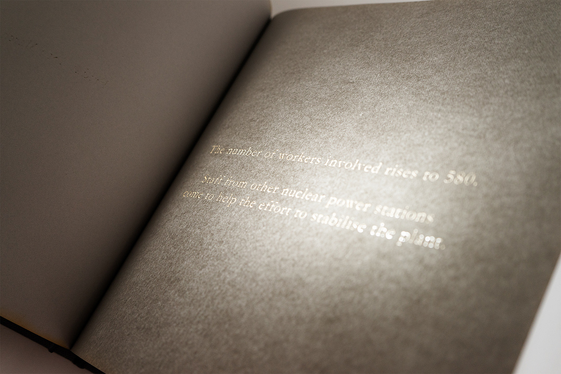 A close-up of one of the pages in the book. Text has been laser-engraved into dark grey paper. It reads 
