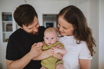 Mann og kvinne inne i et hus holder en baby mellom seg