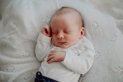 Baby ligger på hvitt teppe og sover