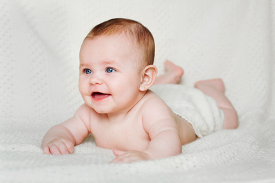 Baby ligger på magen på hvitt teppe