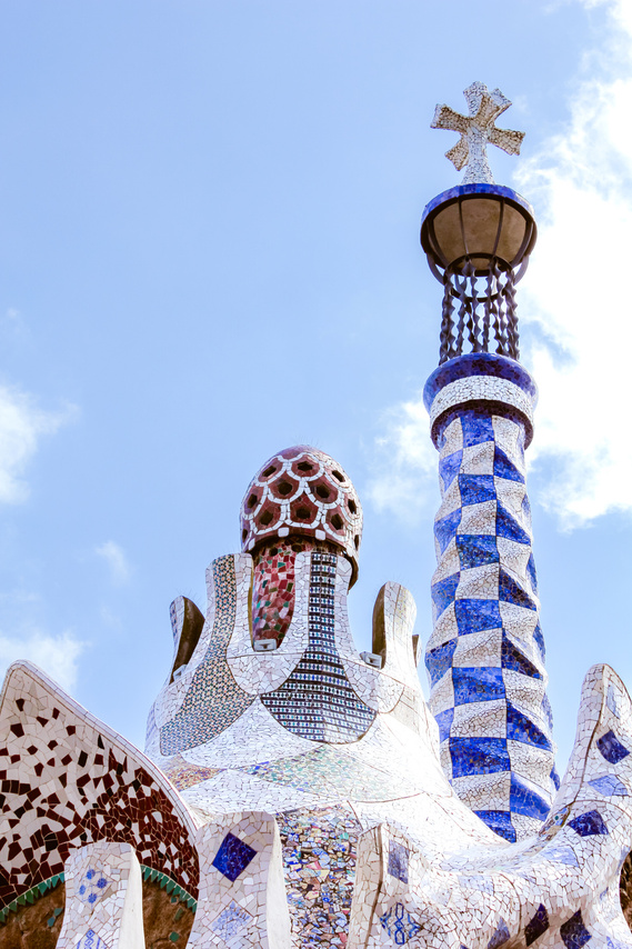 Close-up view from below of the geometric blue and white ceramic tile work architecture towers and abstract buildings under a summer blue sky by Antoni Gaudi at Park Guell in Barcelona