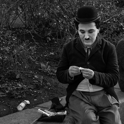 'A street performer dressed as charlie chaplin rolling cigarette, Black & White London Street Photography'