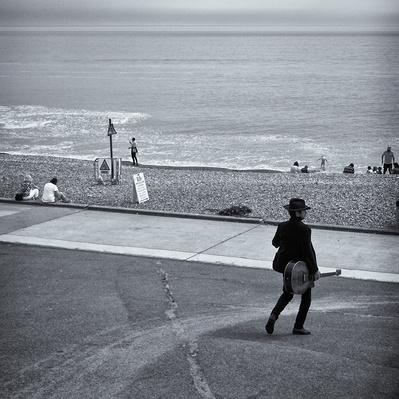 Man walking with his guitar down to the seafront, Rottingdean Sussex black-and-white photography