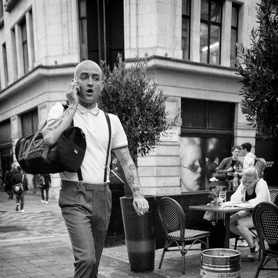'Suedhead walking down the street carrying a bag on his shoulder,Black & White London Street Photography'