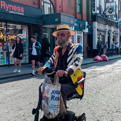 A man on his mobility scooter going down Berwick Street, Soho, London, black-and-white photography