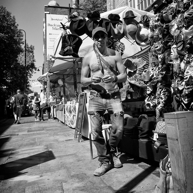 'Market trader standing by his stall bare chested, Black & White London Street Photography'