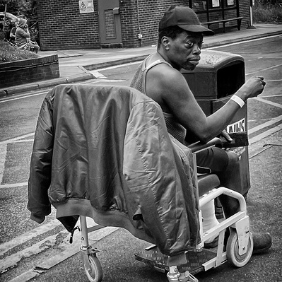 Man in a wheelchair at St George's Hospital Tooting smoking a cigarette black-and-white photography