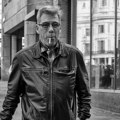 A man in a leather jacket with a cigarette hanging out of his mouth, London black-and-white photography