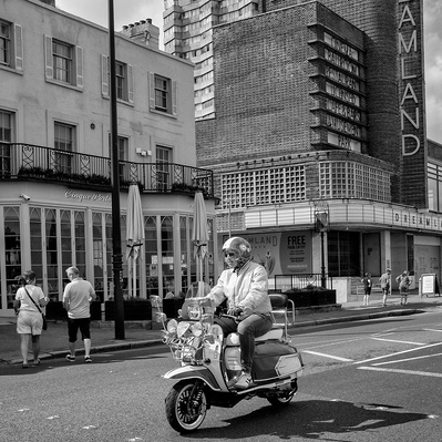 They man on a scooter riding past Dreamland Margate Kent England black-and-white photography