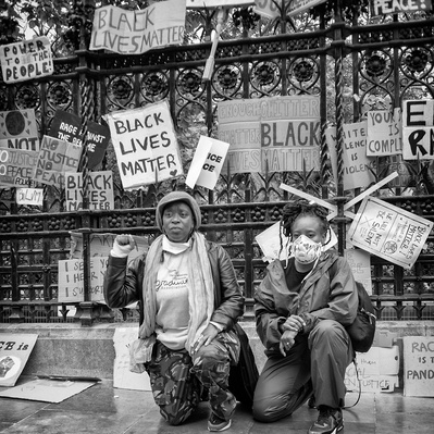 'Women holding placards outside houses of parliament at the Black Lives Matter Protest, Black and White London Street Photography'