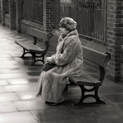 'Lady sitting on a bench smoking wearing a fur coat' Black & White London Street Photography,