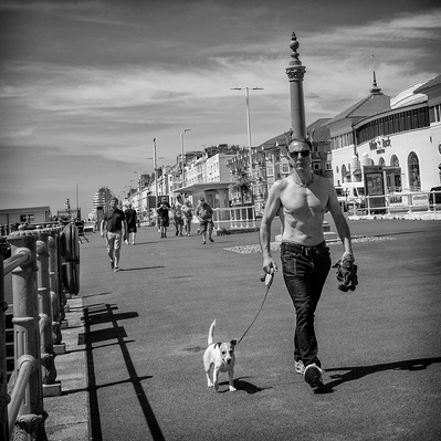 A man walking his dog along Brighton seafront, Brighton, Sussex, England, black-and-white photograph photography