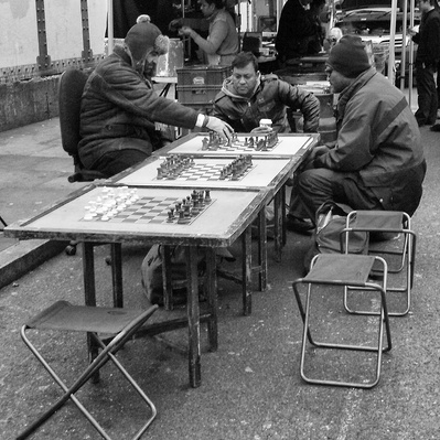 A group of men playing chess in brick Lane East London black-and-white photography