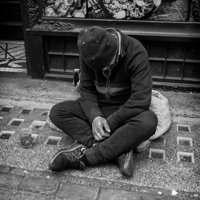Homeless man with legs crossed London black-and-white photography