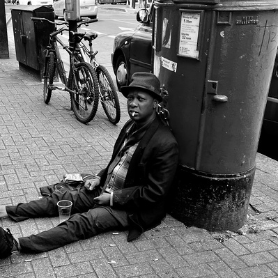 Man sitting down having a rest and a drink Tooting South London black-and-white photography