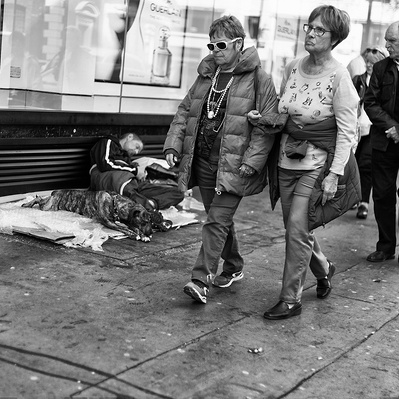 People walking by a rough sleeper with his dog London black-and-white photography