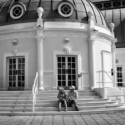 A couple sitting on the steps outside Worthing  pier Sussex England black-and-white photography