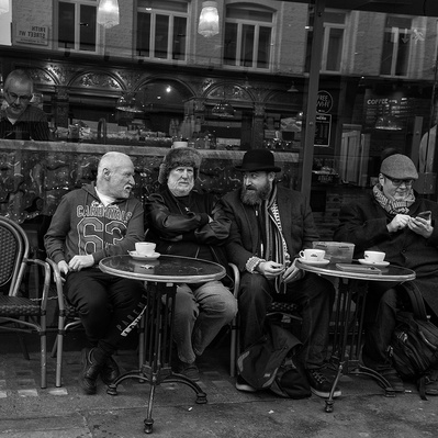Four men sitting outside a coffee shop in old Compton Street, Soho, London black-and-white photography