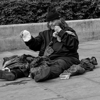 Rough sleeper sitting on pavement, London black-and-white for photography
