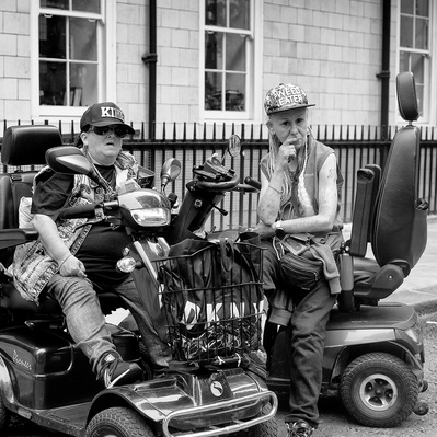 Two women sitting on their mobility scooters, Soho, London black-and-white photography