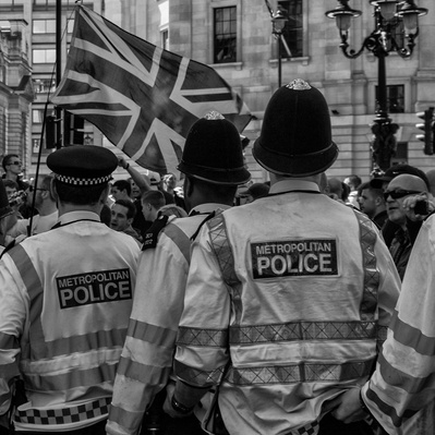 'Police watch as Tommy Robinson Supporters walk by, London Black and White Street Photography'