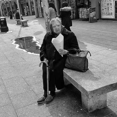An old lady eating a bag of chips, popular East London black-and-white photography