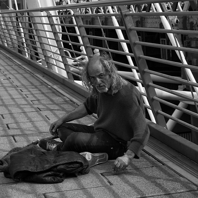 Rough sleeper sitting on the millennium Bridge London black-and-white photography