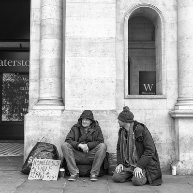 Two rough sleepers with placard asking money for somewhere to sleep London black-and-white photography