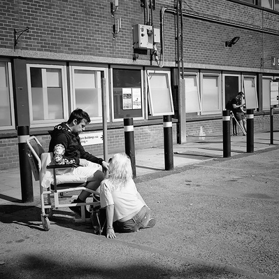 Move a man sitting outside St George's hospital department, South London black-and-white photography