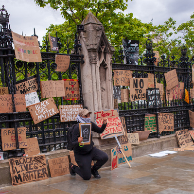 'Woman holding a banner outside houses of parliament, London Street Photography Colour'