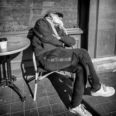 Man sleeping outside coffee shop in the Sun Tooting South London black-and-white photography